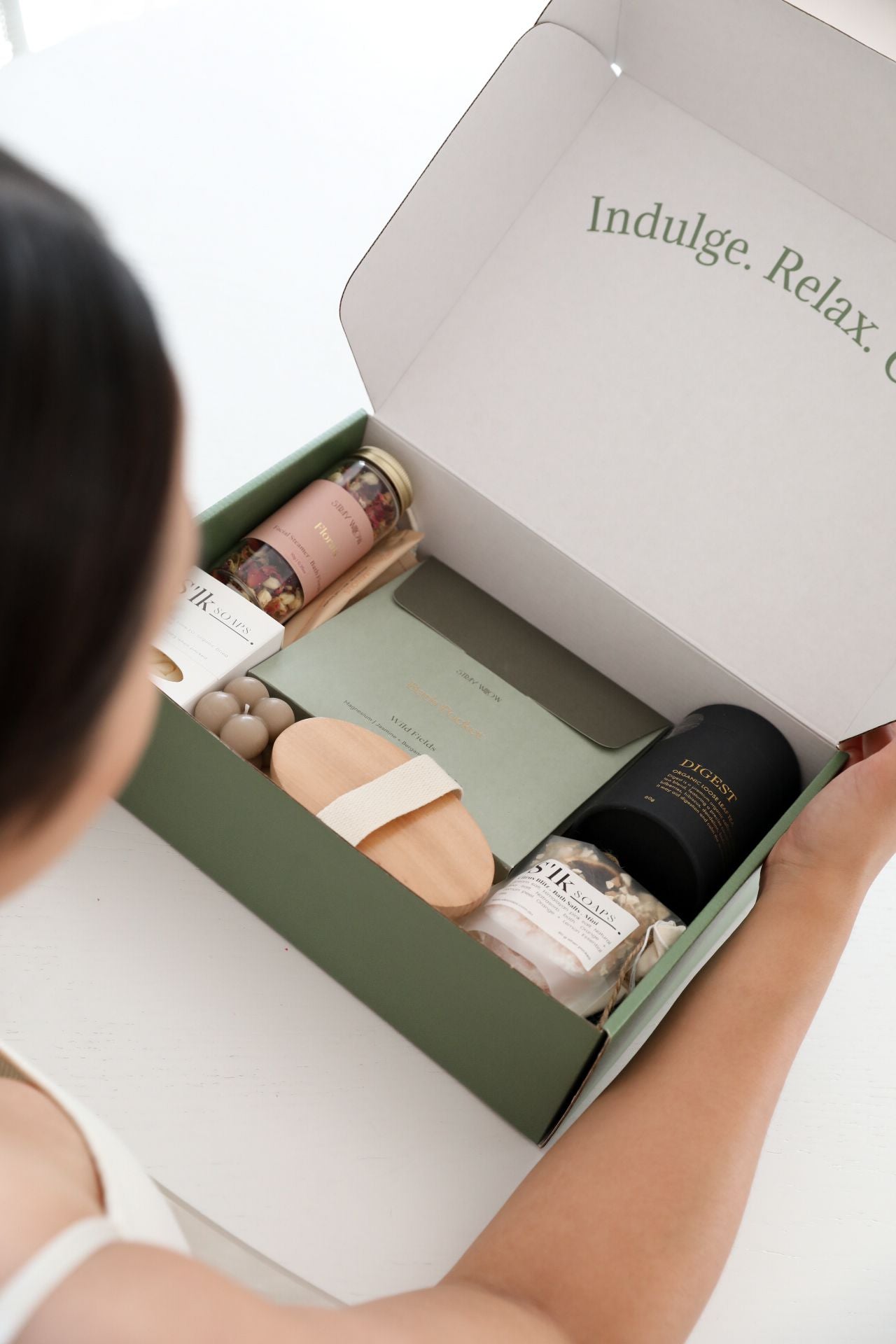 A person opening a wellness gift box filled with wellness products.