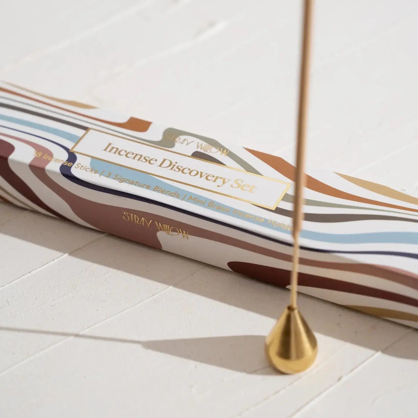 A natural incense discovery set with a single incense stick placed inside a brass incense holder.