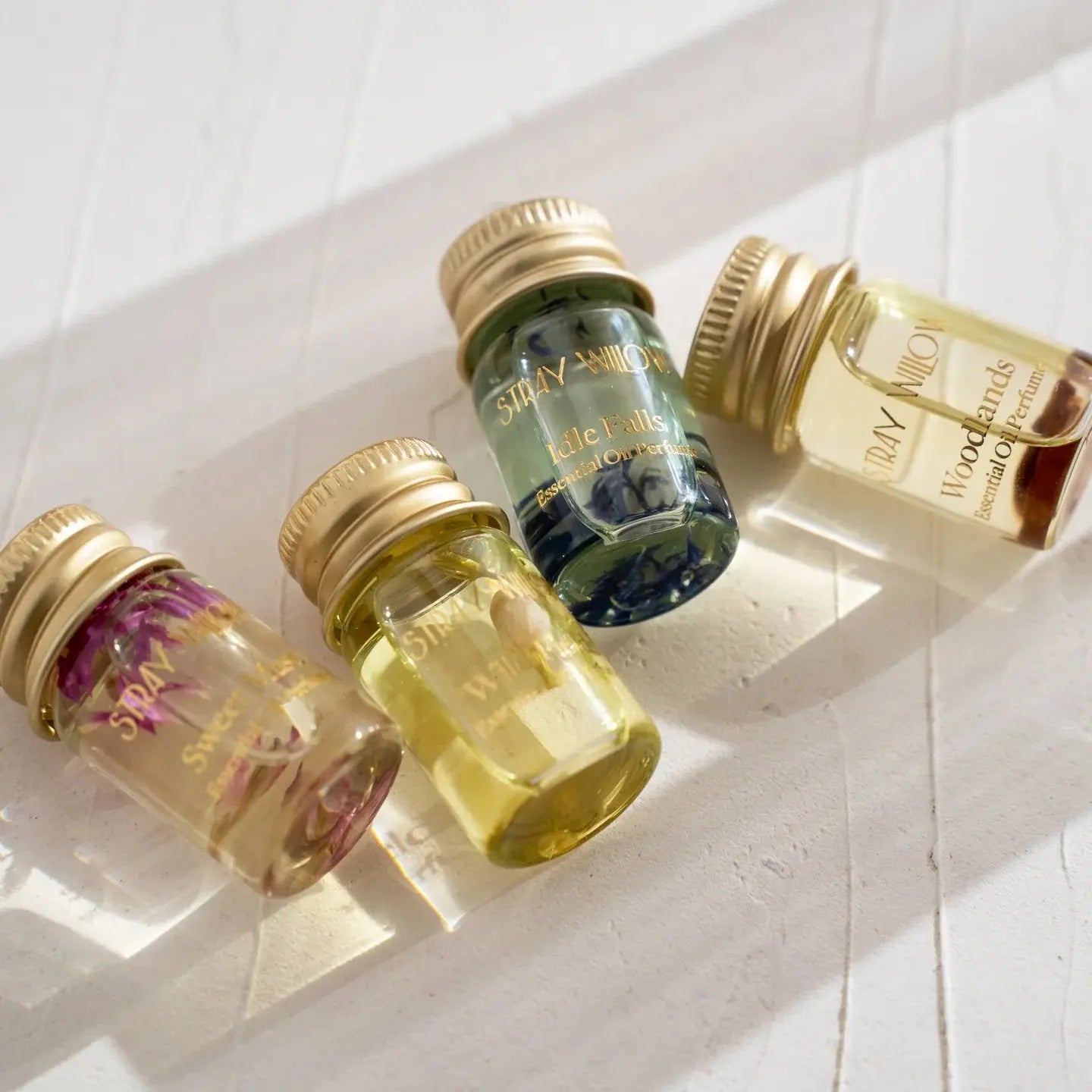 4 vials of perfume set laid flat on a white background with gold lids